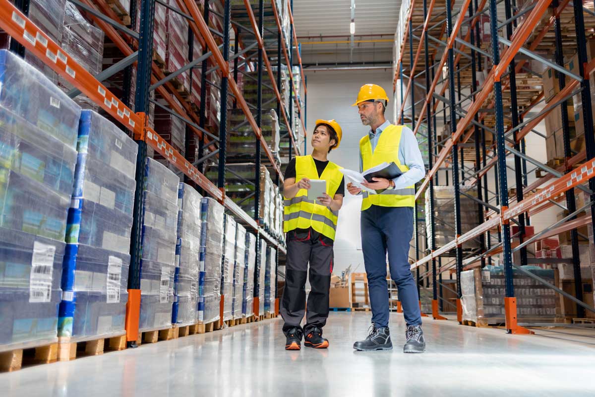 Warehouseman and manager looking at packages in large warehouse